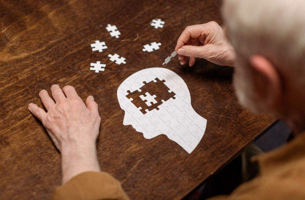 An elderly man suffering from memory loss is doing a puzzle activity at our senior living community.