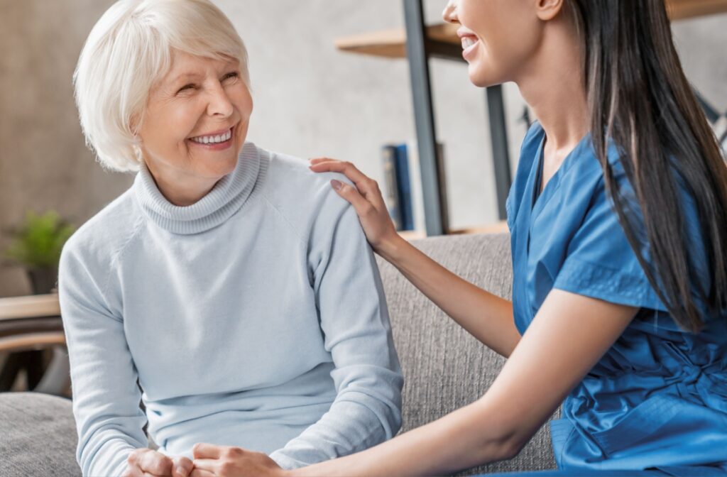 A resident in assisted living smiling while a caregiver checks in on them.